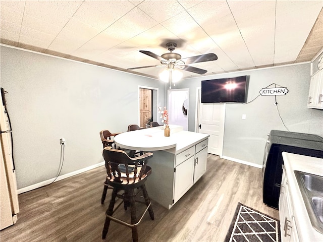 kitchen with hardwood / wood-style floors, white cabinetry, a center island, and ceiling fan