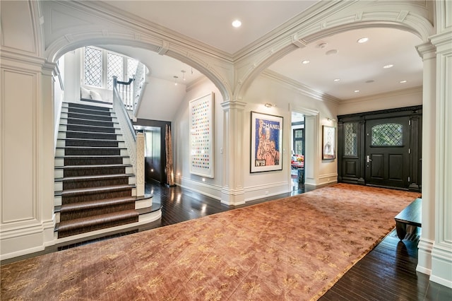 entrance foyer with ornamental molding, dark hardwood / wood-style floors, and ornate columns