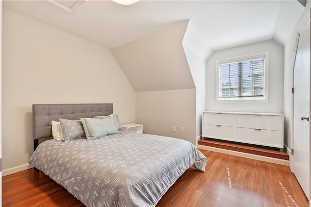 bedroom with vaulted ceiling and hardwood / wood-style floors