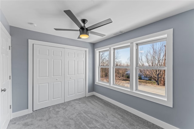 unfurnished bedroom with light colored carpet, ceiling fan, and a closet