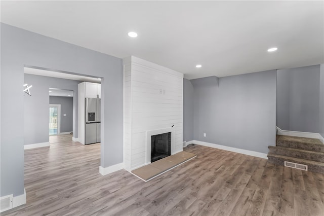 unfurnished living room featuring a large fireplace and light hardwood / wood-style flooring