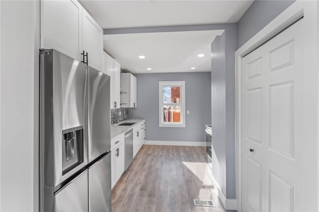 kitchen with white cabinetry, appliances with stainless steel finishes, sink, and light wood-type flooring