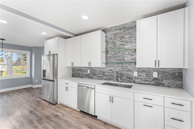 kitchen with stainless steel appliances, white cabinets, decorative backsplash, sink, and light wood-type flooring