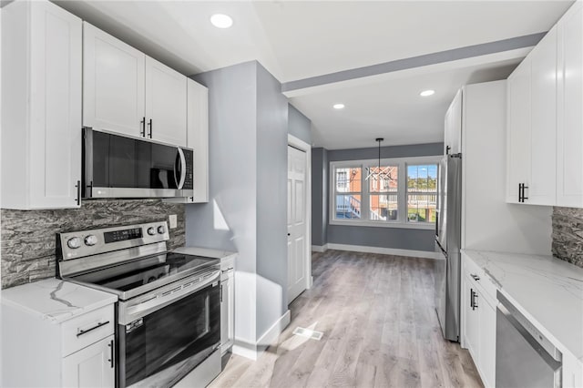 kitchen with white cabinets, light stone counters, decorative light fixtures, and appliances with stainless steel finishes