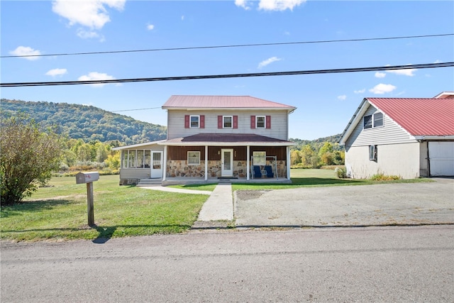 view of front of house featuring a mountain view, covered porch, and a front yard