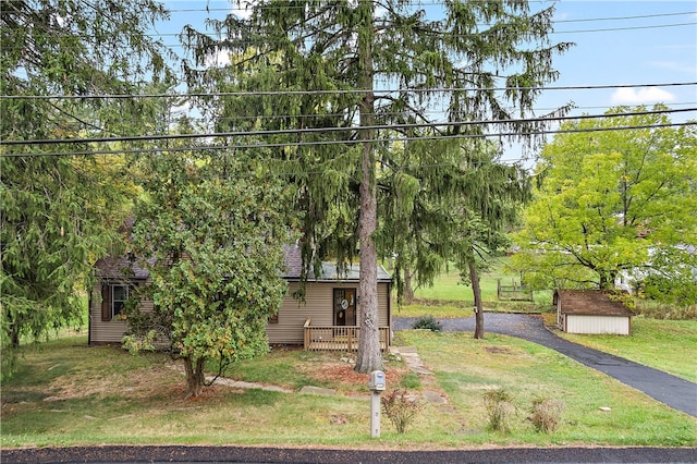 view of property hidden behind natural elements with a front yard and a shed