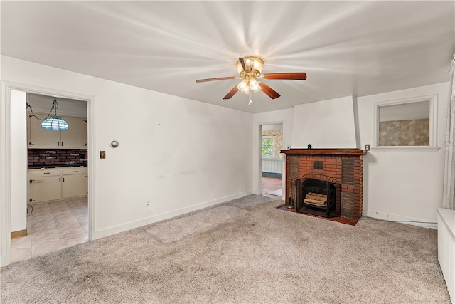 unfurnished living room with ceiling fan, light colored carpet, and a brick fireplace