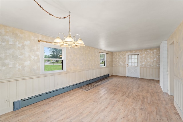 unfurnished room with an inviting chandelier, a baseboard radiator, and light hardwood / wood-style flooring