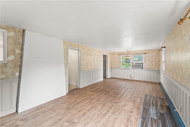 unfurnished room featuring cooling unit, an inviting chandelier, and hardwood / wood-style floors