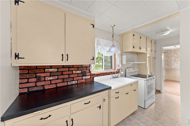 kitchen featuring cream cabinetry, decorative backsplash, pendant lighting, white range with electric cooktop, and sink