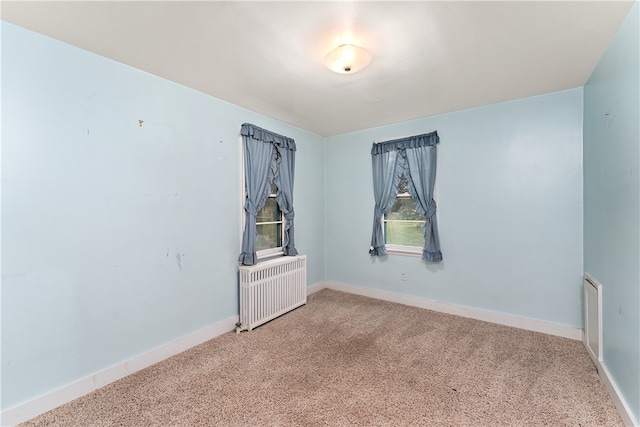 carpeted empty room featuring radiator heating unit