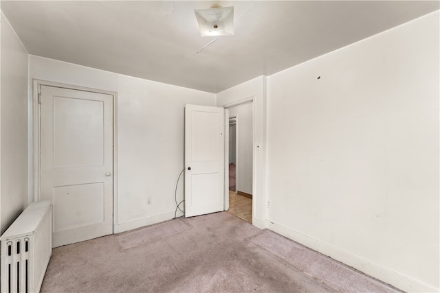 unfurnished bedroom featuring light colored carpet and radiator