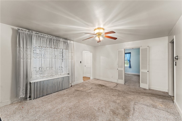 spare room with ceiling fan, radiator, and carpet