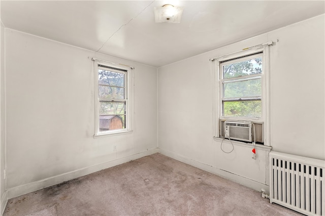 spare room with radiator, a wealth of natural light, and light colored carpet