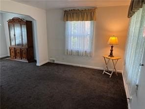 spare room featuring dark colored carpet