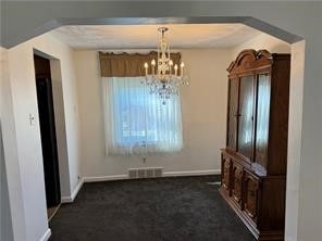 unfurnished dining area with dark carpet and a chandelier