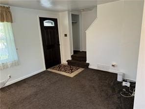 entrance foyer featuring dark colored carpet