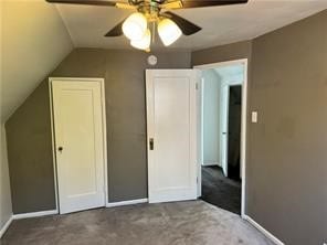 unfurnished bedroom featuring ceiling fan, carpet flooring, and vaulted ceiling