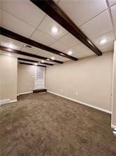 basement featuring a paneled ceiling and dark carpet