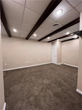 basement with a drop ceiling and dark colored carpet