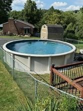 view of swimming pool featuring a storage shed and a wooden deck