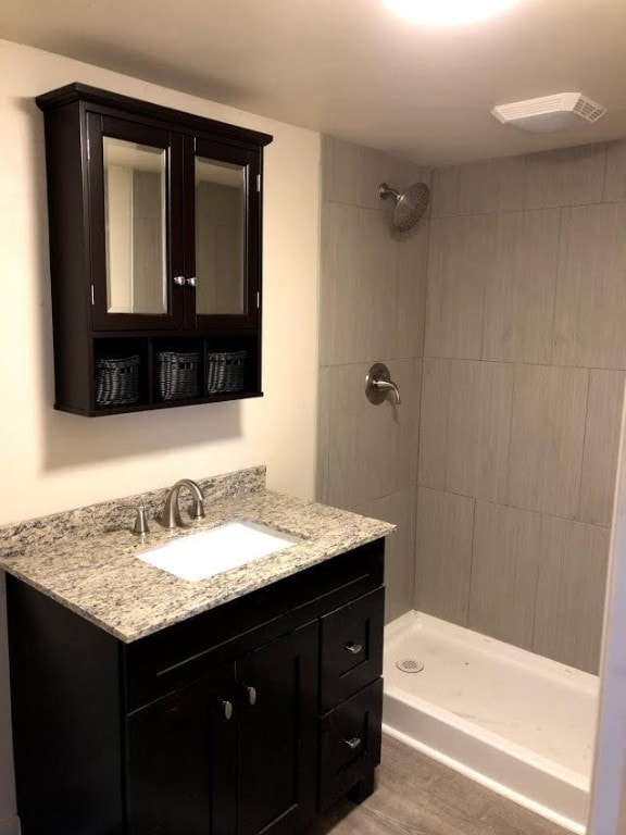 bathroom with tiled shower, vanity, and hardwood / wood-style flooring