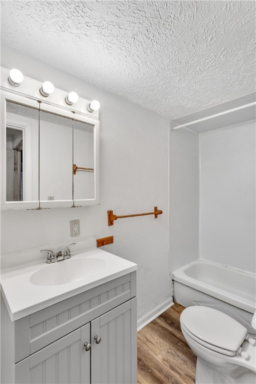 bathroom with vanity, toilet, a textured ceiling, and hardwood / wood-style flooring