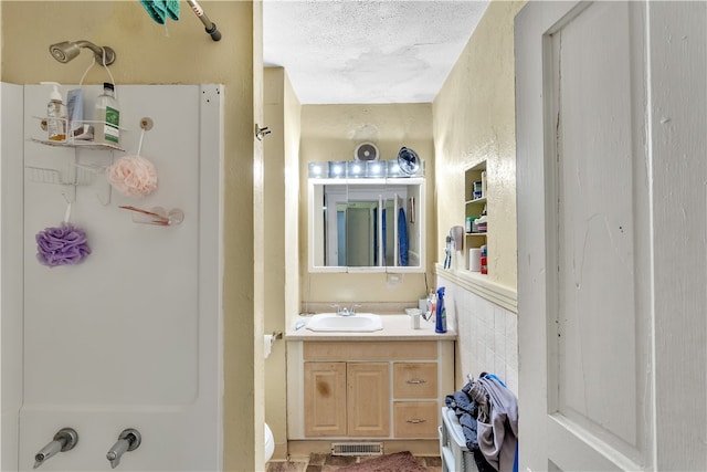 full bathroom with a textured ceiling, washtub / shower combination, vanity, and toilet