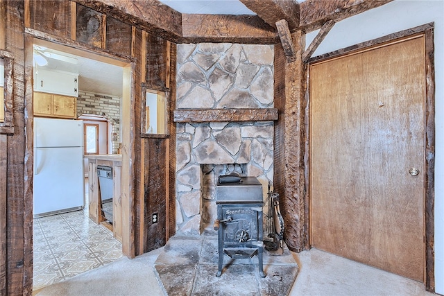 unfurnished living room with a wood stove and beamed ceiling