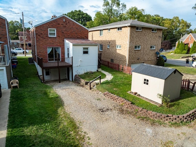 back of property featuring driveway, an outbuilding, a storage shed, a garage, and a yard