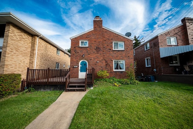 back of house with brick siding, a chimney, a deck, and a yard