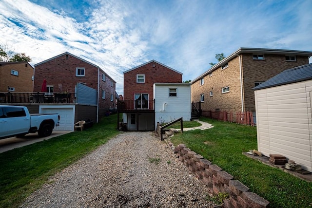 back of house featuring an outbuilding, fence, gravel driveway, and a yard
