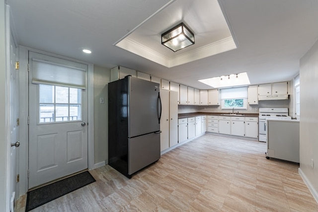 kitchen featuring white cabinets, white range, a wealth of natural light, and stainless steel fridge