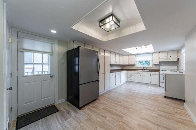 kitchen featuring under cabinet range hood, a raised ceiling, white range with gas cooktop, and freestanding refrigerator