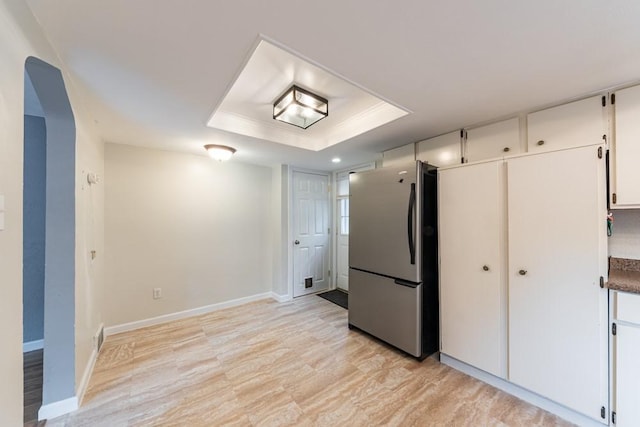 kitchen with light wood finished floors, baseboards, white cabinetry, a tray ceiling, and freestanding refrigerator