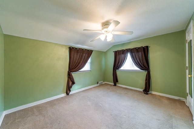 spare room featuring baseboards, vaulted ceiling, a ceiling fan, and light colored carpet