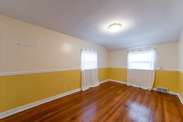 unfurnished room featuring baseboards, visible vents, lofted ceiling, and wood-type flooring