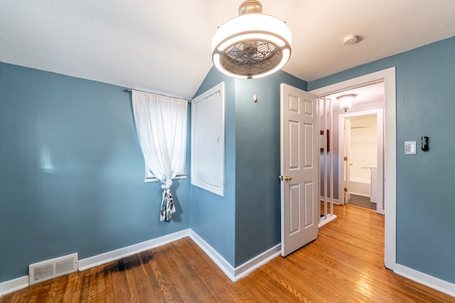 unfurnished room featuring lofted ceiling and hardwood / wood-style floors