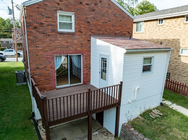 back of property with cooling unit, brick siding, a lawn, and a wooden deck