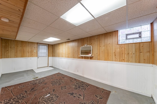 basement with a paneled ceiling and wooden walls