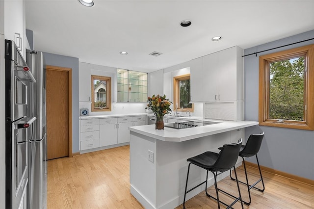 kitchen featuring white cabinetry, a breakfast bar, kitchen peninsula, and black electric cooktop