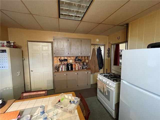 kitchen with a drop ceiling, tile counters, and white appliances