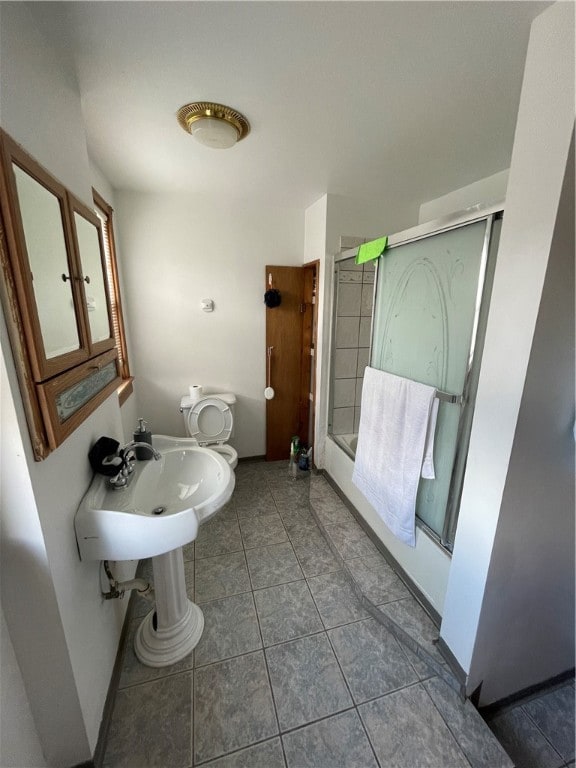 bathroom featuring shower / bath combination with glass door, toilet, and tile patterned floors