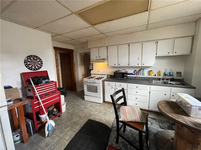 kitchen featuring a drop ceiling, white range with gas cooktop, sink, and white cabinets