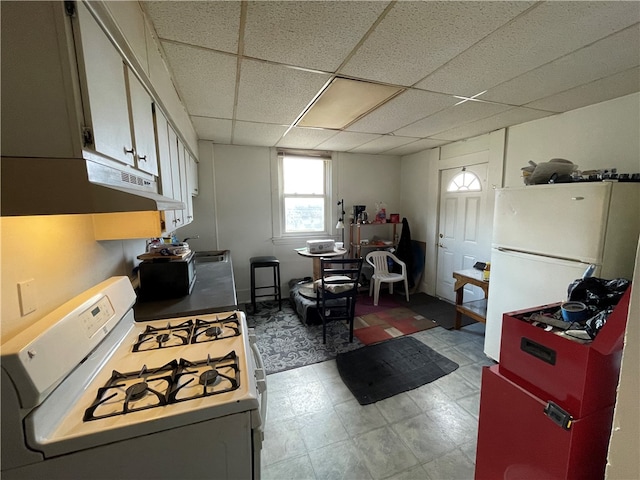 kitchen with a paneled ceiling and white appliances