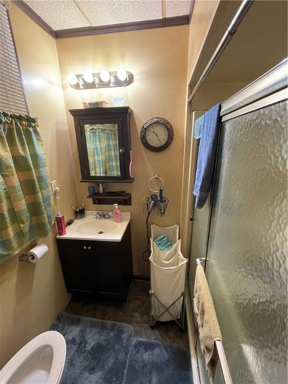 bathroom featuring ornamental molding, a shower with door, vanity, and toilet