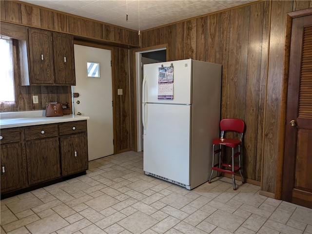 kitchen with wood walls, dark brown cabinets, and white refrigerator