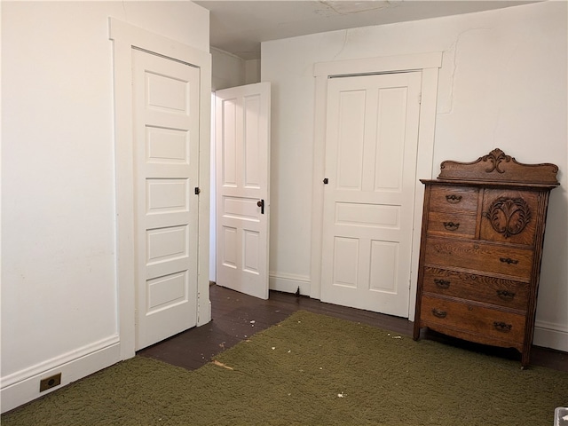 unfurnished bedroom featuring a closet and dark carpet