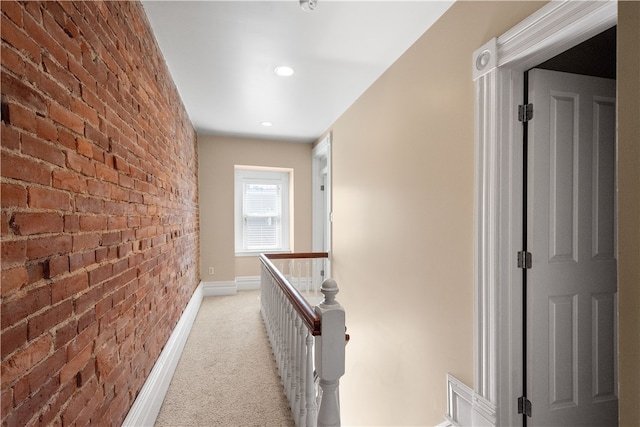 hallway with light carpet and brick wall