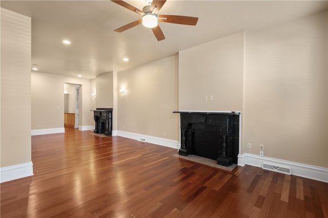 unfurnished living room featuring ceiling fan, wood-type flooring, and a fireplace